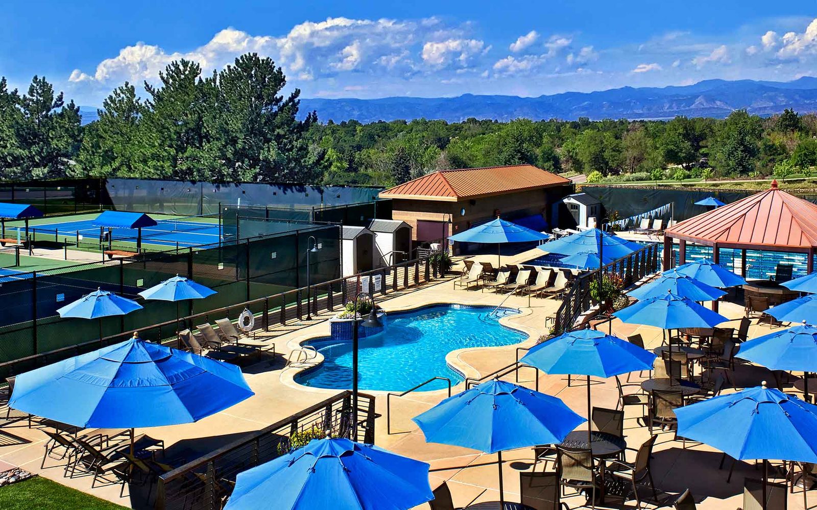 The pool and tennis courts at Club Greenwood with the Front Range beyond