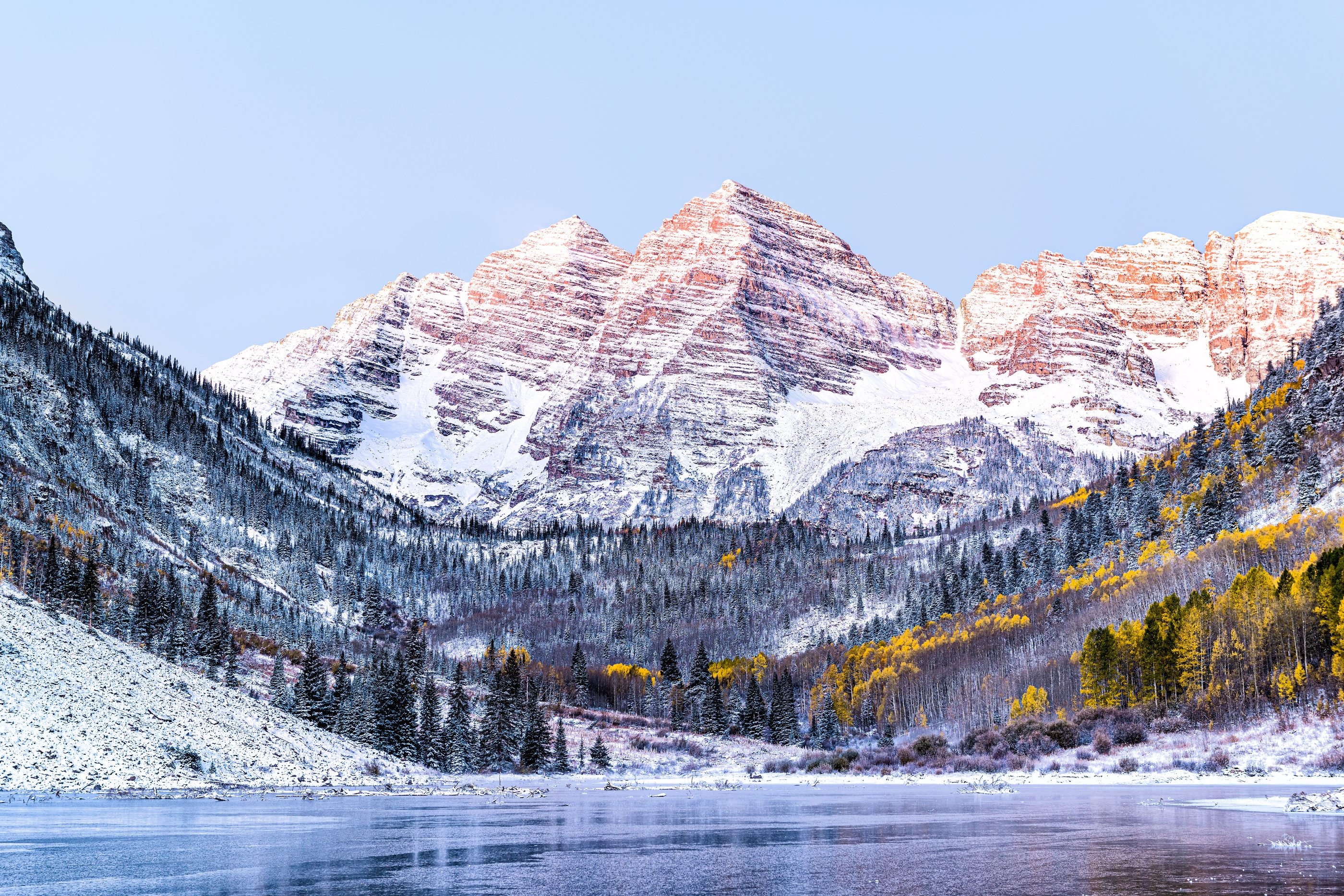 First light on the Maroon Bells above a snow covered valley