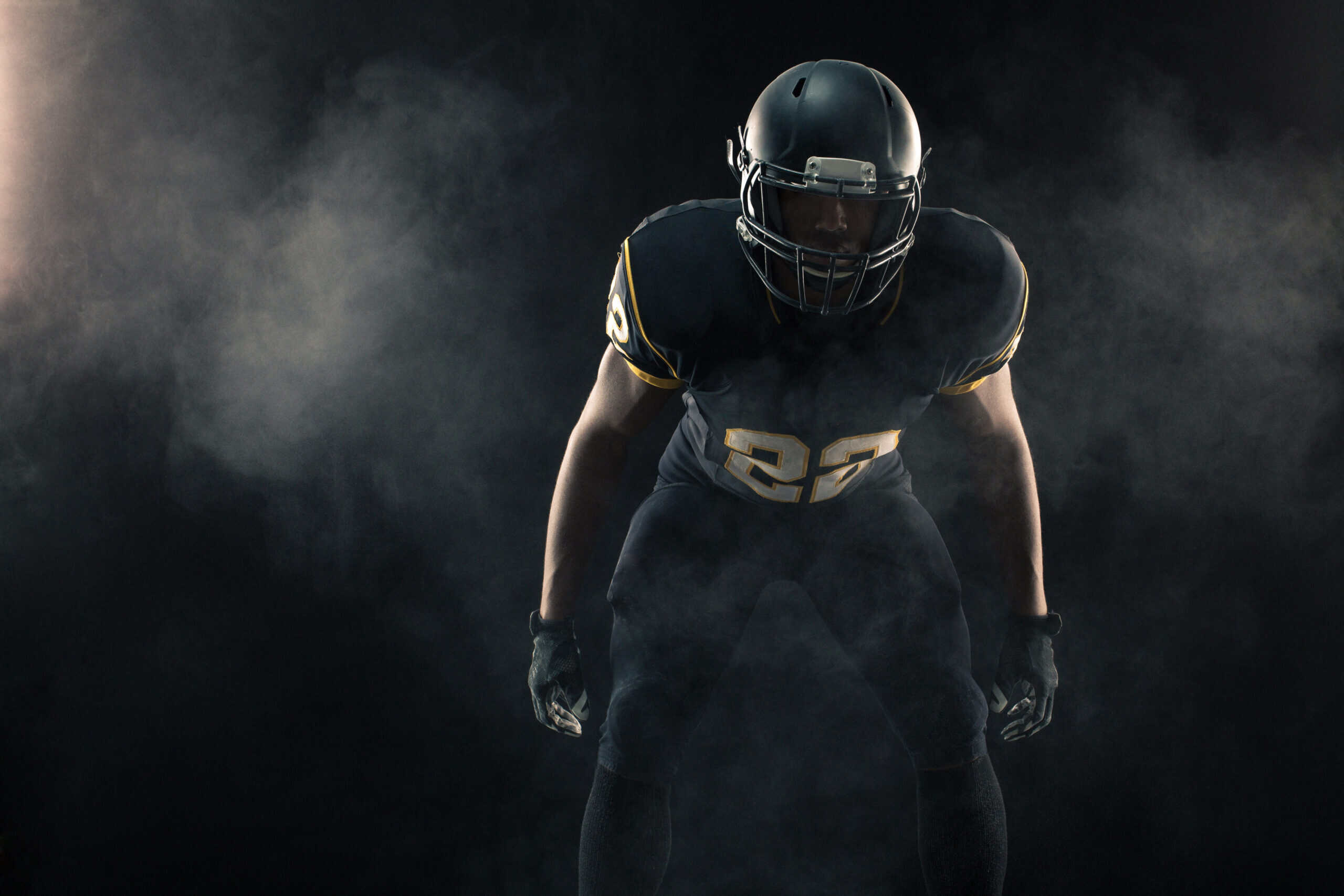 A football player in dramatic light, ready to compete.